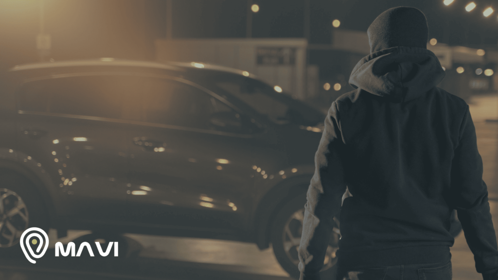Auto en riesgo de robo durante una encerrona nocturna; persona encapuchada acercándose al vehículo, imagen de seguridad vehicular para prevenir portonazos y autos robados en Chile con Mavi.
