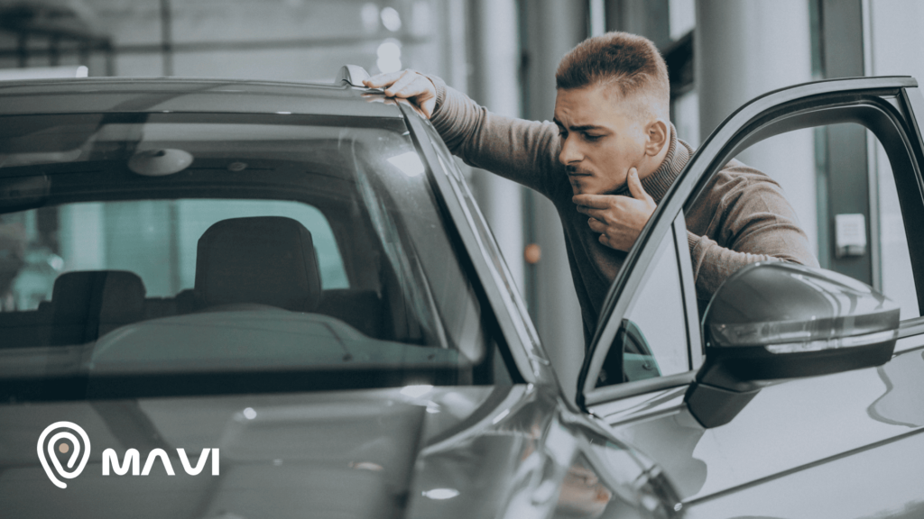Hombre inspeccionando un auto usado para verificar cómo saber si un auto es robado antes de comprarlo.