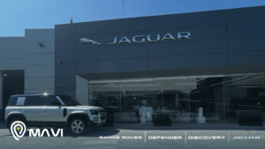 Fachada de concesionario Jaguar Land Rover con un Land Rover Defender estacionado, acompañado por Mavi GPS en una jornada de experiencia y seguridad vehicular.