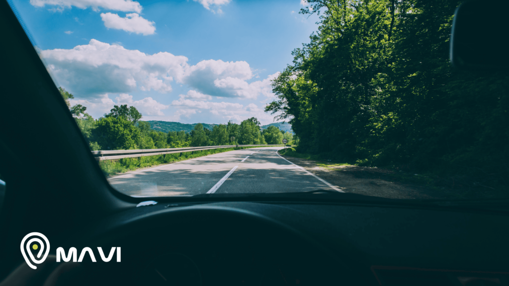 Vista desde el interior de un auto en la ruta durante las vacaciones de verano en Chile, con paisaje natural y sistema de seguridad Mavi.