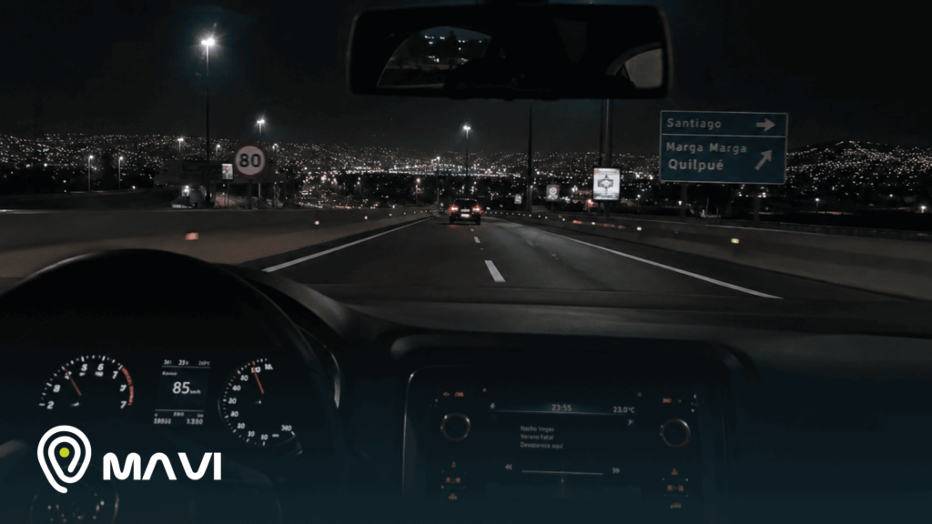 Vista desde el interior de un vehículo circulando por una autopista durante la noche, con luces de la ciudad al fondo y señalética vial. La imagen transmite movimiento, monitoreo y seguridad en los desplazamientos por San Bernardo y sus alrededores.