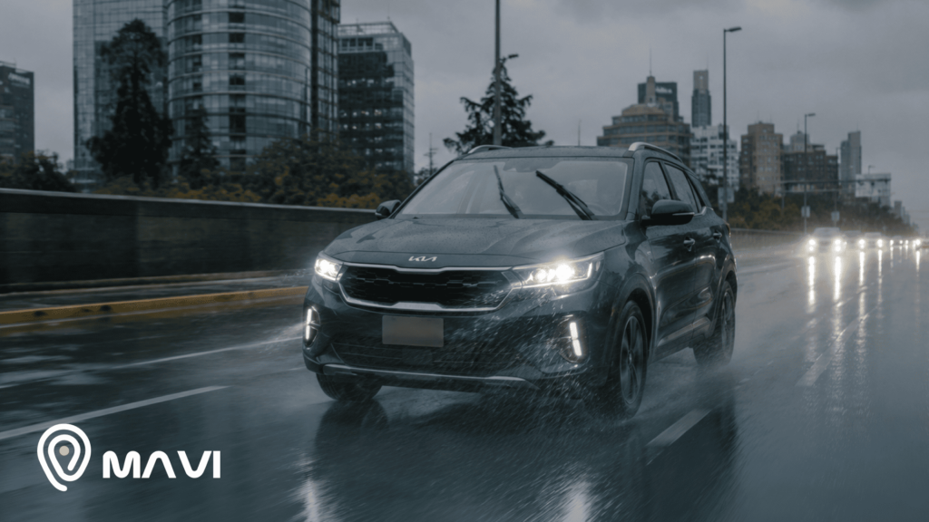 SUV circulando bajo la lluvia en una avenida urbana, con pavimento mojado y baja visibilidad. La imagen representa la conducción en condiciones climáticas adversas y la importancia de mantenerse informado con la Dirección Meteorológica de Chile.