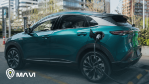 Auto eléctrico conectado a una estación de carga en un entorno urbano moderno. La imagen representa la movilidad sustentable y el uso de tecnología en autos eléctricos.